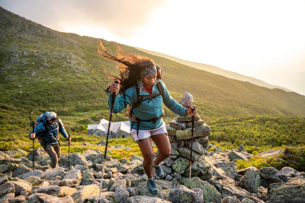 A woman and man hiking at sunset.