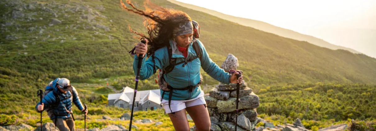 A woman and man hiking at sunset.