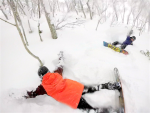 Two snowboarders enjoying a powder day after a snowstorm in Niseko Moiwa, Japan.